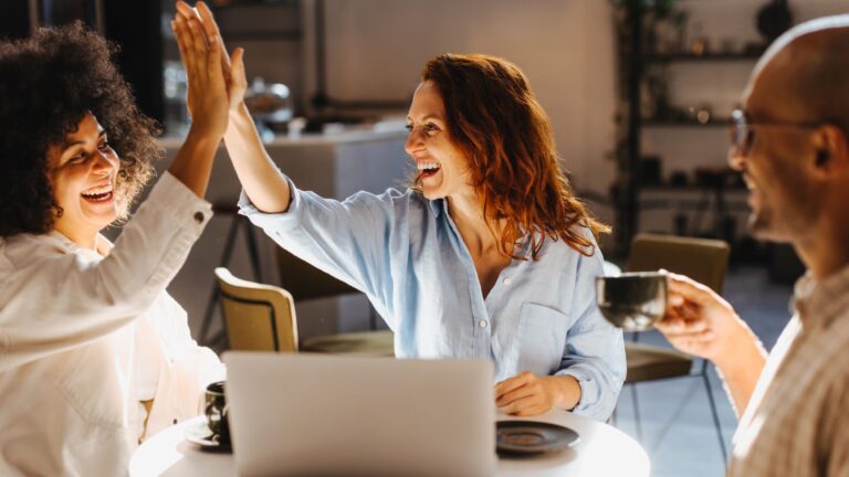 successful-team-high-fiving-in-a-coffee-shop