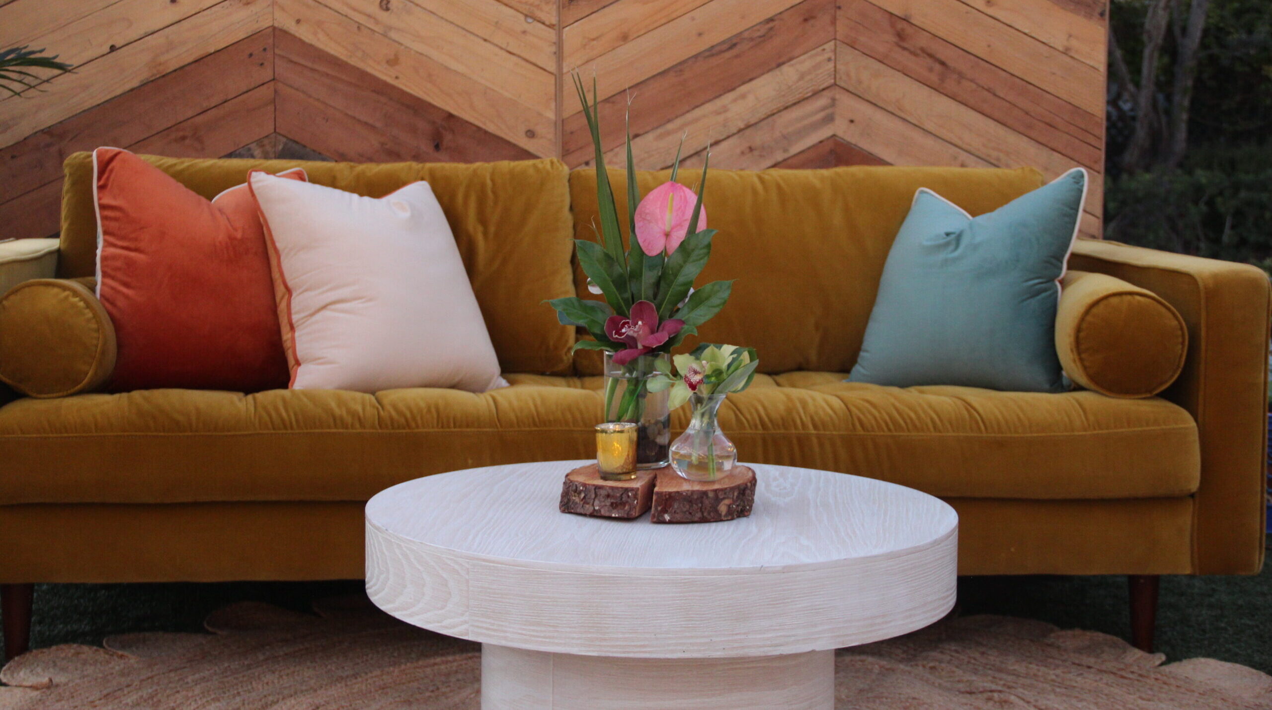 florals on white table in front of mustard yellow couch with reclaimed wood backdrop